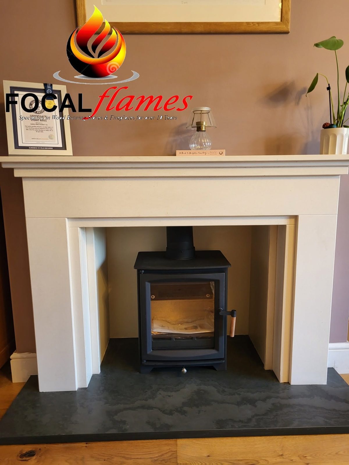 A wood burner fitted inside a cream timber surround on a slate hearth