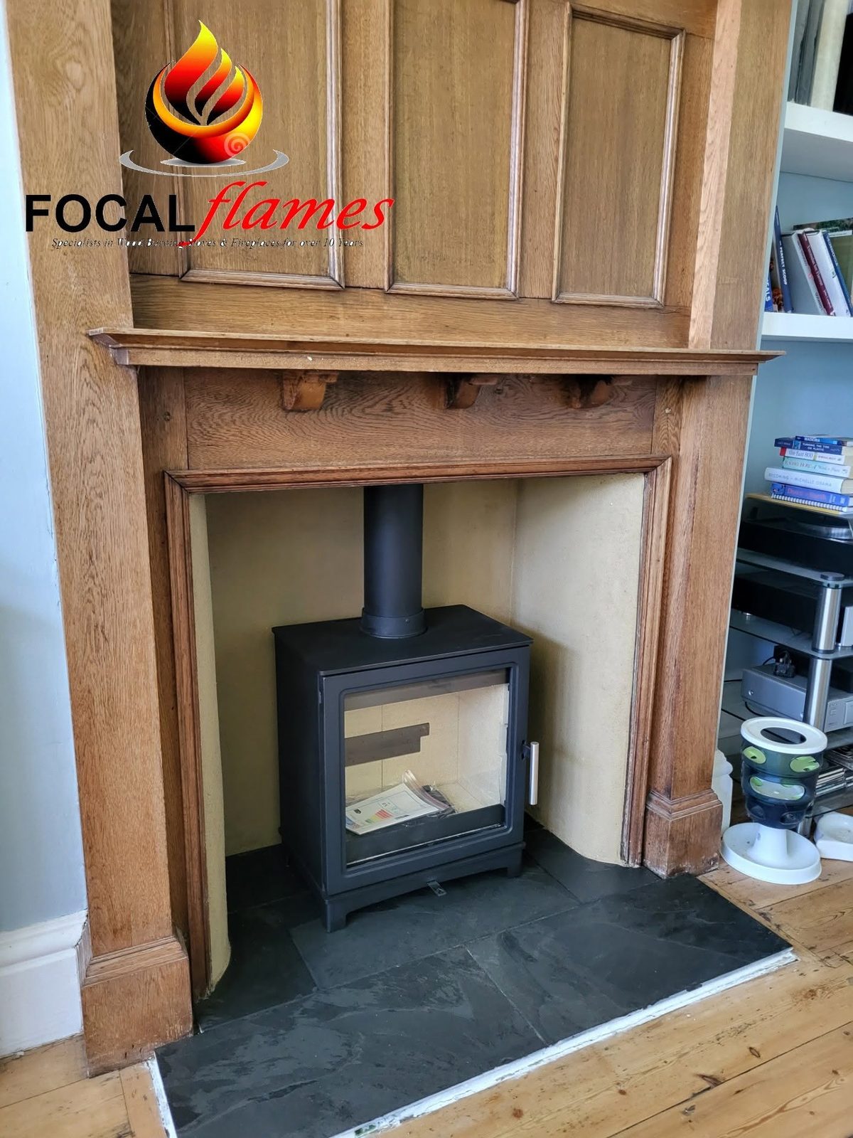 A stove inside a tall carved timber surround on a slate hearth