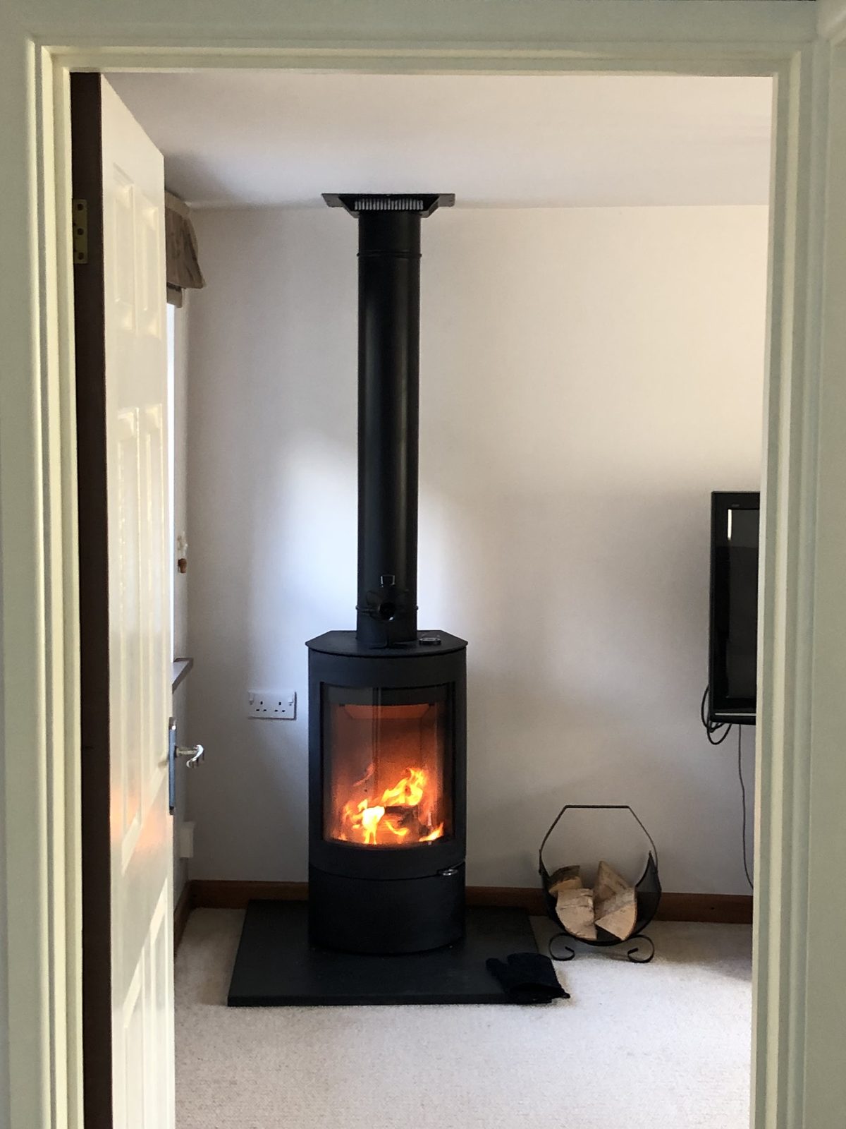 A customer's tall round stove with its flue, seen through a doorway