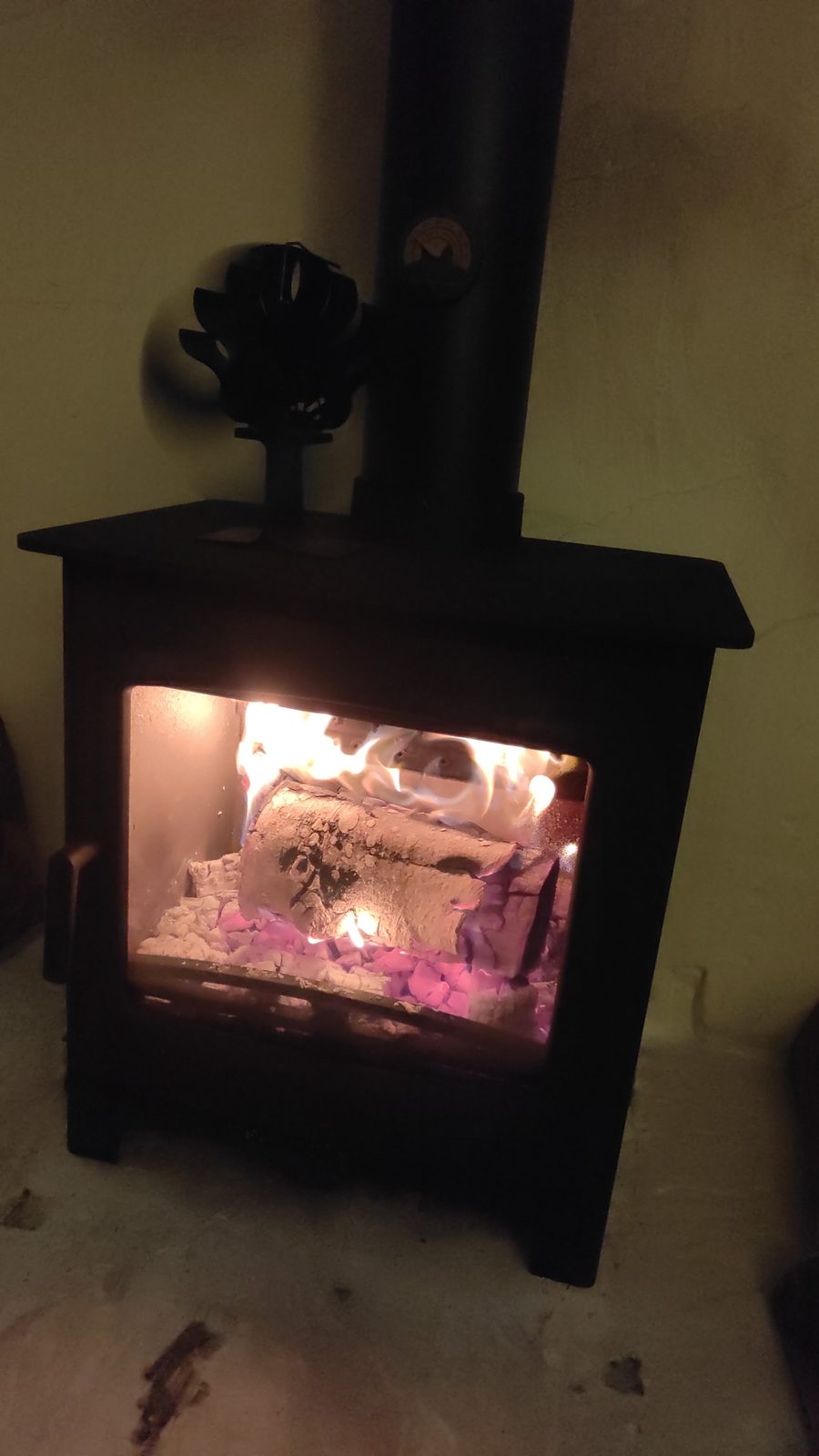 A customer's stove burning at night with a stove fan on top